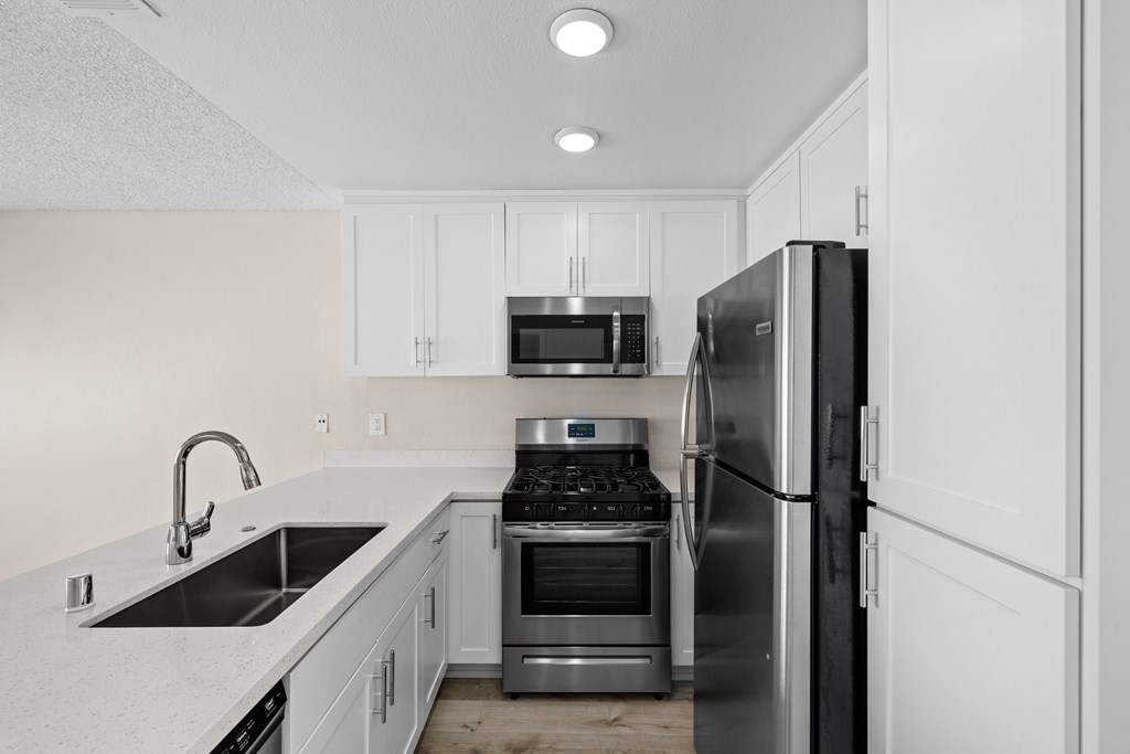 A modern kitchen with a sink, stove, and refrigerator.