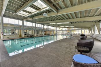 a swimming pool in a building with chairs and tables