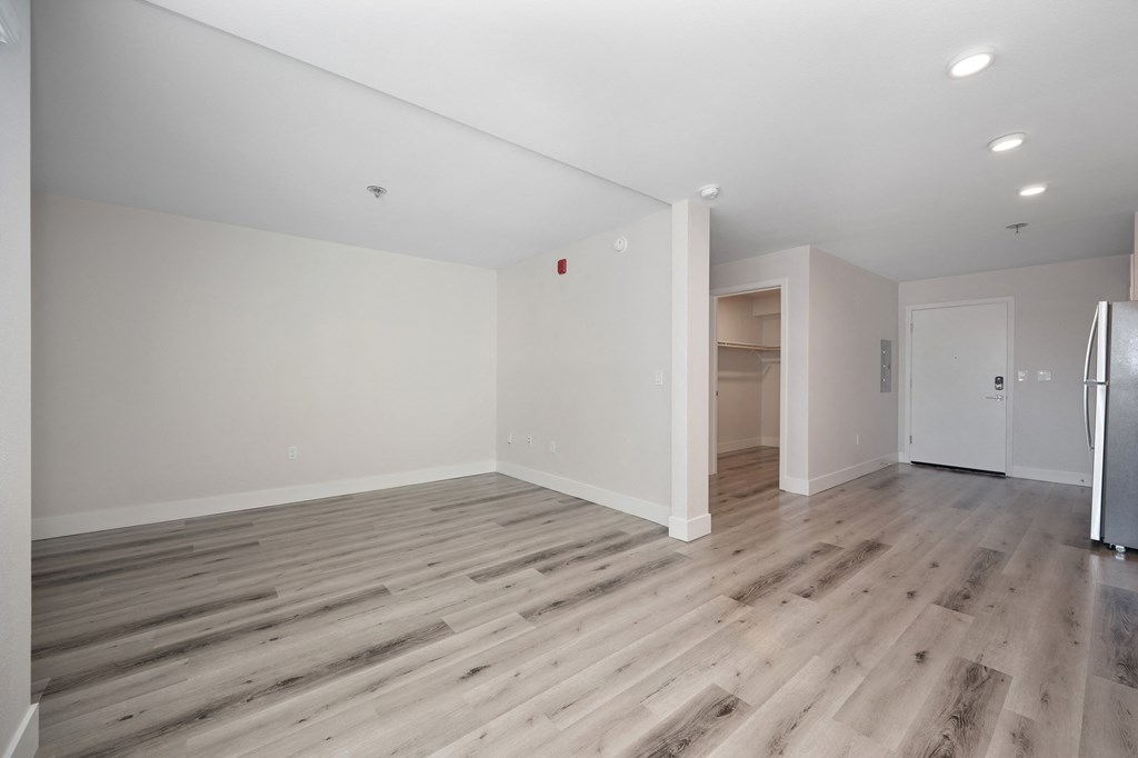 a living room with white walls and wood flooring and a refrigerator  at Track 281 Apartments, Sacramento, 95811