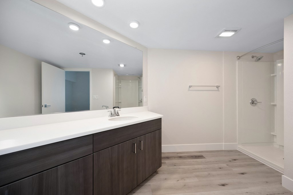 a bathroom with a large mirror and a sink and a shower  at Track 281 Apartments, Sacramento, CA