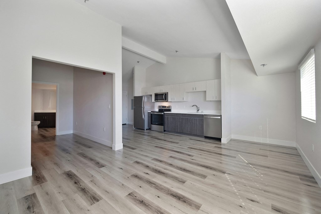 an empty living room with hardwood floors and a kitchen  at Track 281 Apartments, Sacramento