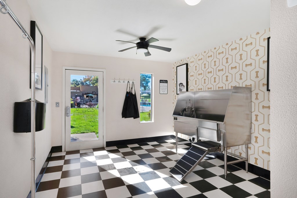 A black and white checkered floor in a room with a fan and a refrigerator.