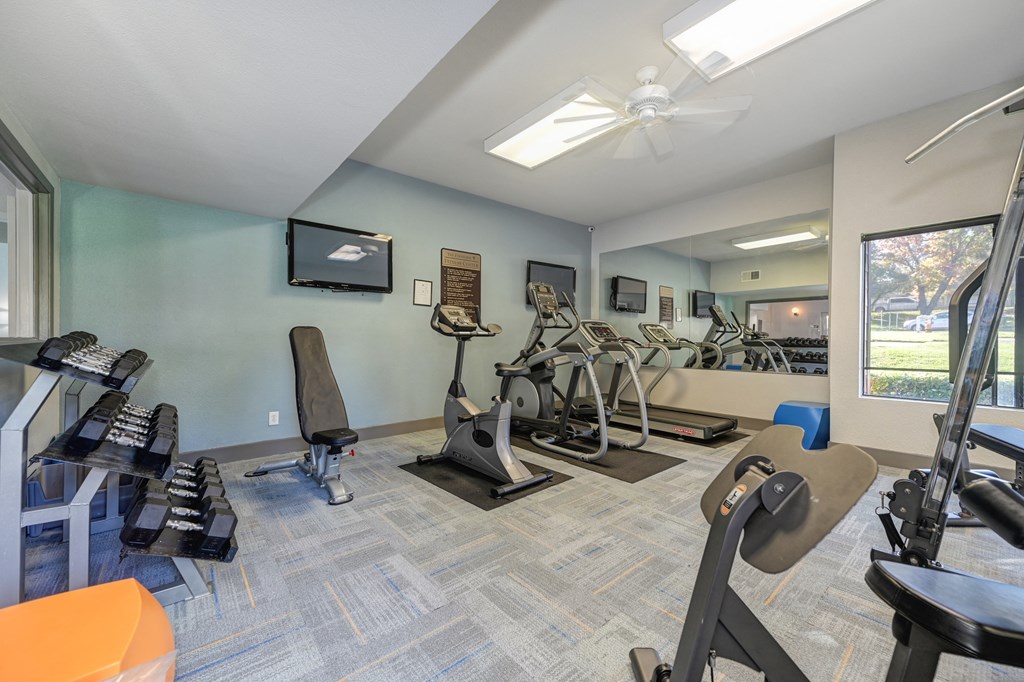 Community Fitness Center.  The Room has a light blue accent wall and contains a weight system, elliptical machines, treadmill, bench and free weights.at Fountains of Fair Oaks, Fair Oaks
