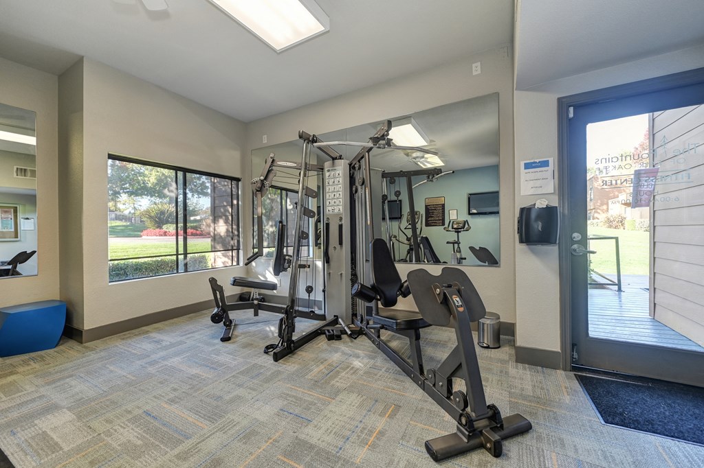 Fitness center entrance.  Room has large weight systems, carpeting, mirrors and several windows.at Fountains of Fair Oaks, California