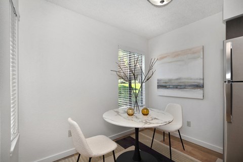 a small dining room with two white chairs and a marble table with two vases on it at Fountains of Fair Oaks, Fair Oaks