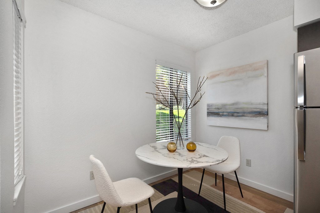 a small dining room with two white chairs and a marble table with two vases on it a small dining room with two white chairs and a marble table with two vases on it at Fountains of Fair Oaks, Fair Oaks