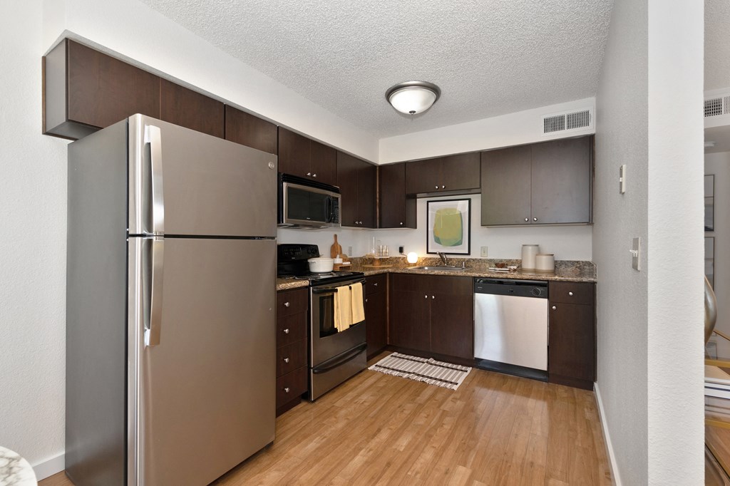 a kitchen with dark wood cabinets and stainless steel appliances at Fountains of Fair Oaks, Fair Oaks California