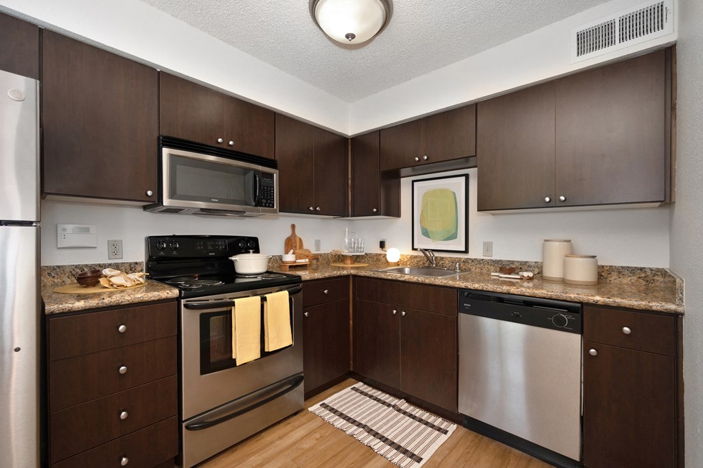 a kitchen with dark wood cabinets and stainless steel appliances at Fountains of Fair Oaks, Fair Oaks, 95628