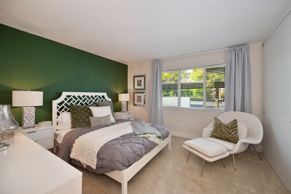 a bedroom with a bed and a chair with dark green accent wall and large window at Folsom Ranch, California, 95630