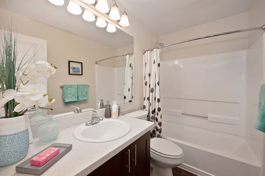 a bathroom with a sink vanity with quartz counters, a toilet and a shower at Folsom Ranch Apartments in California