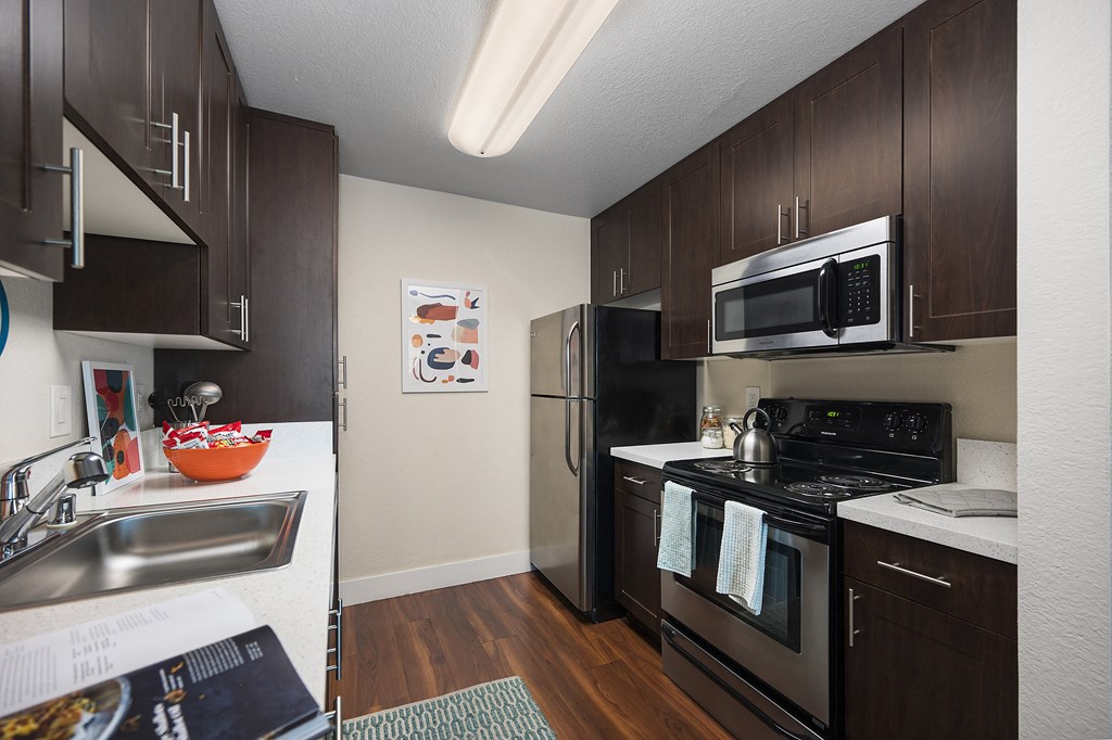 a kitchen with dark wood cabinets and stainless steel appliances at Folsom Ranch, Folsom