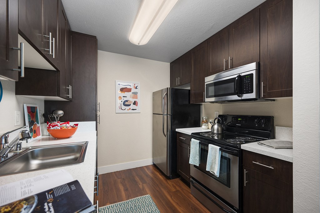 a kitchen with dark wood cabinets and stainless steel appliances at Folsom Ranch, California, 95630