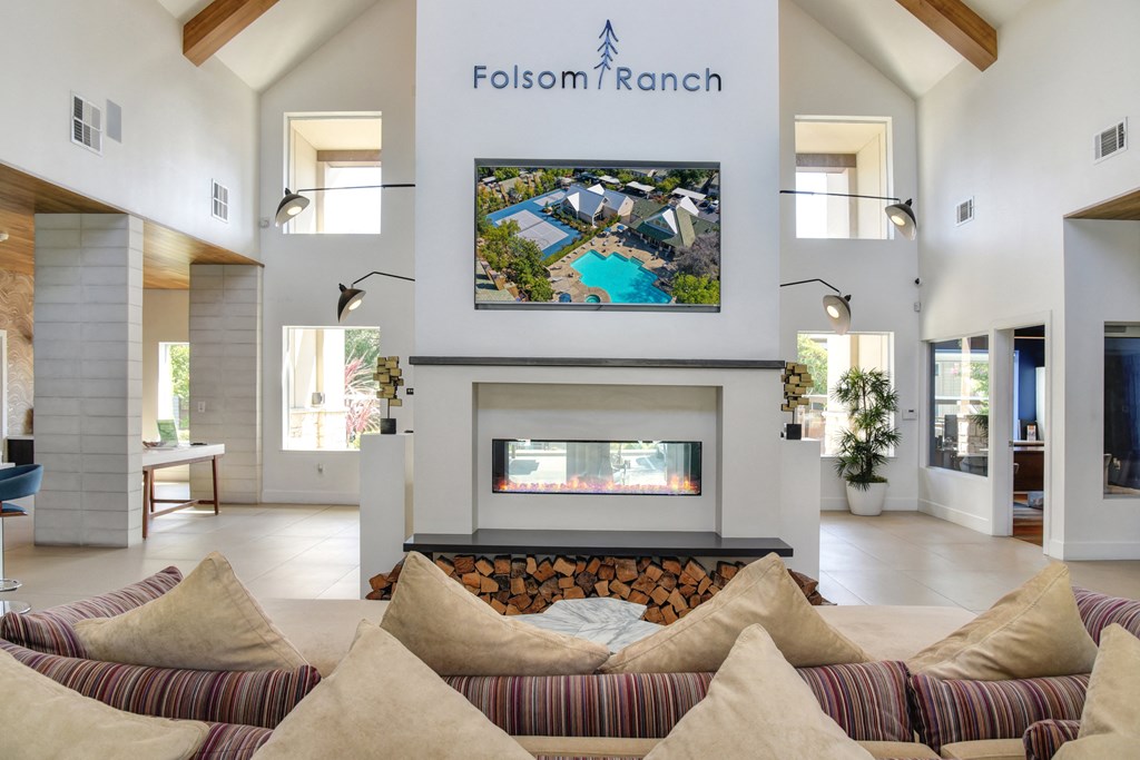 Community Leasing Office Lounge Area with Hardwood Inspired Floor, couch and chairs and Mounted Flat Screen TV above the fireplace.at Folsom Ranch, Folsom, CA, 95630