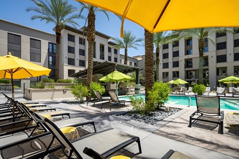 A pool area with sun loungers and umbrellas.