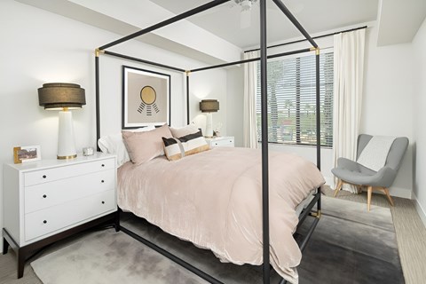 A bedroom with a four poster bed, a chair, and a dresser.