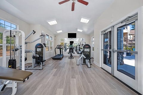 A gym with a variety of equipment including treadmills, weights, and a bench.