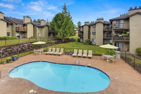 A swimming pool surrounded by a fence and chairs in a residential area.