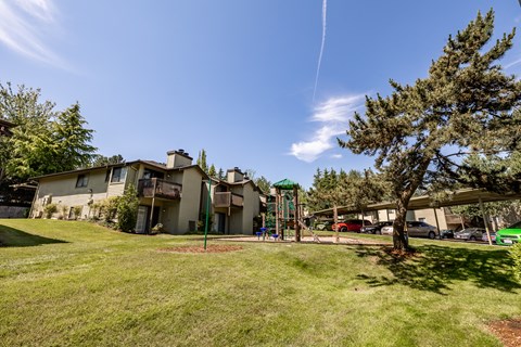 Property grounds showing green grass , play structure and apt