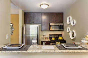 Model kitchen with granite countertops, stainless appliances and darker brown cabinetry - Photo Gallery 2