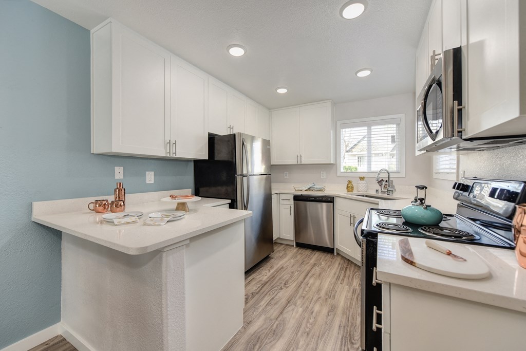 Kitchen with Hardwood Inspired Floor, White Cabinets, Microwave and Dishwasher at The Legacy Apartments, Antelope, CA, 95843