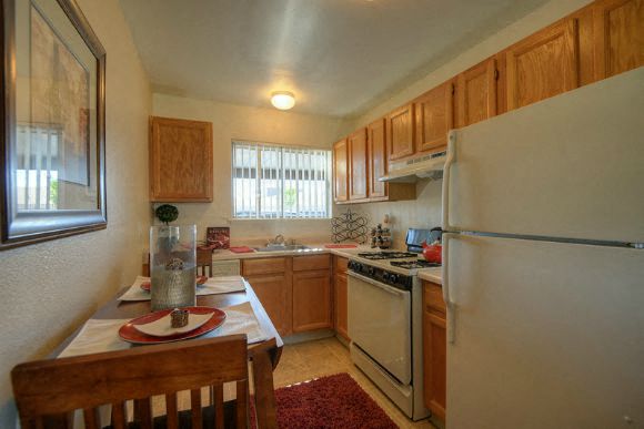 Kitchen with Hardwood Inspired Floors, Wood Chairs, Refrigerator, Windows and Wood Cabinets at Olympus Park Apartments, Roseville, California