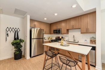 Kitchen Entrance Model home kitchen with stainless steel appliances, hardwood inspired flooring and light brown cabinetry - Photo Gallery 4