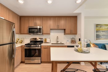 Kitchen and Dining Area Model home kitchen with stainless steel appliances and light brown cabinetry - Photo Gallery 3