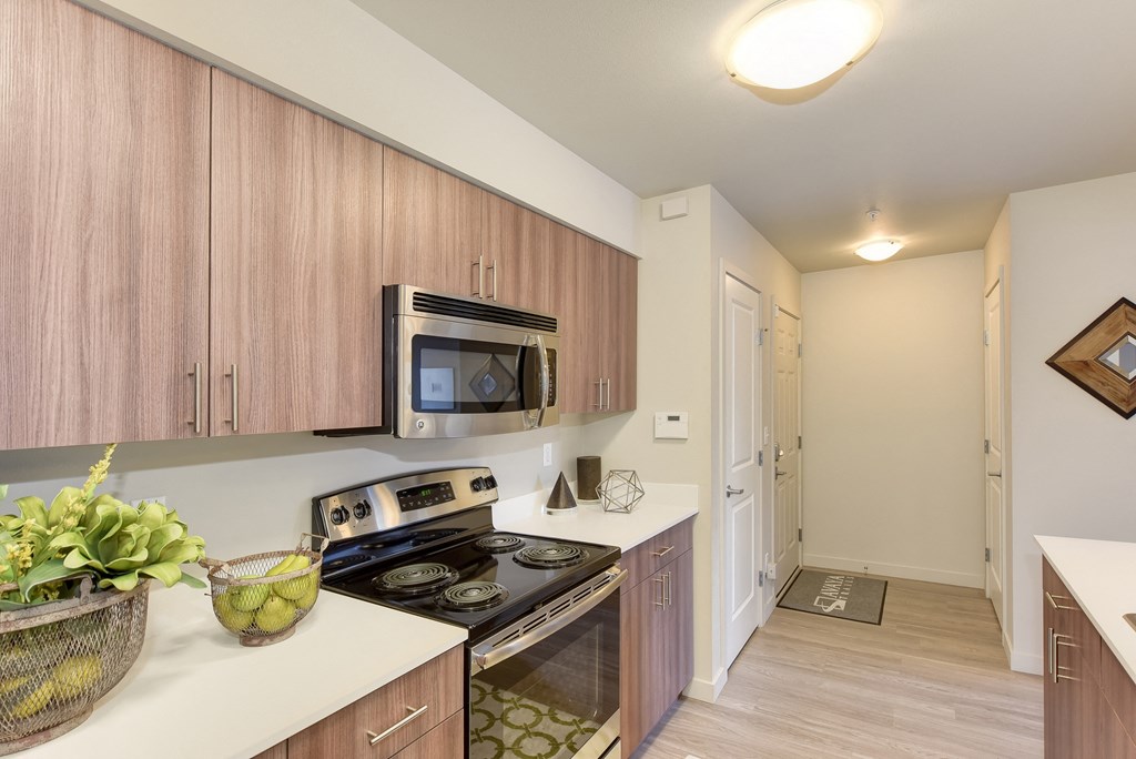 Kitchen with Countertop,MMicrowave, Wood Inspired Floor, Oven, Wood Cabinets, Ceiling Lights, Fruit Bowl