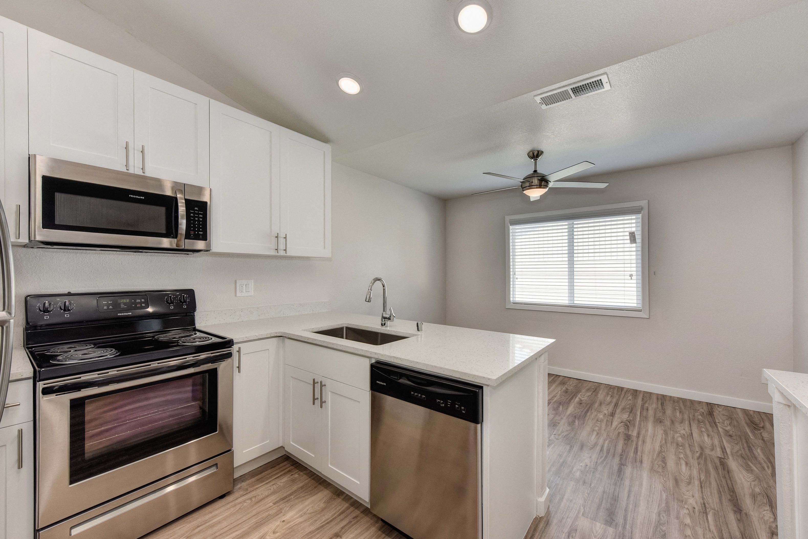 Kitchen with Dishwasher , Hardwood Inspired Floor, Oven, Microwave and Window at The Legacy Apartments, Antelope, CA
