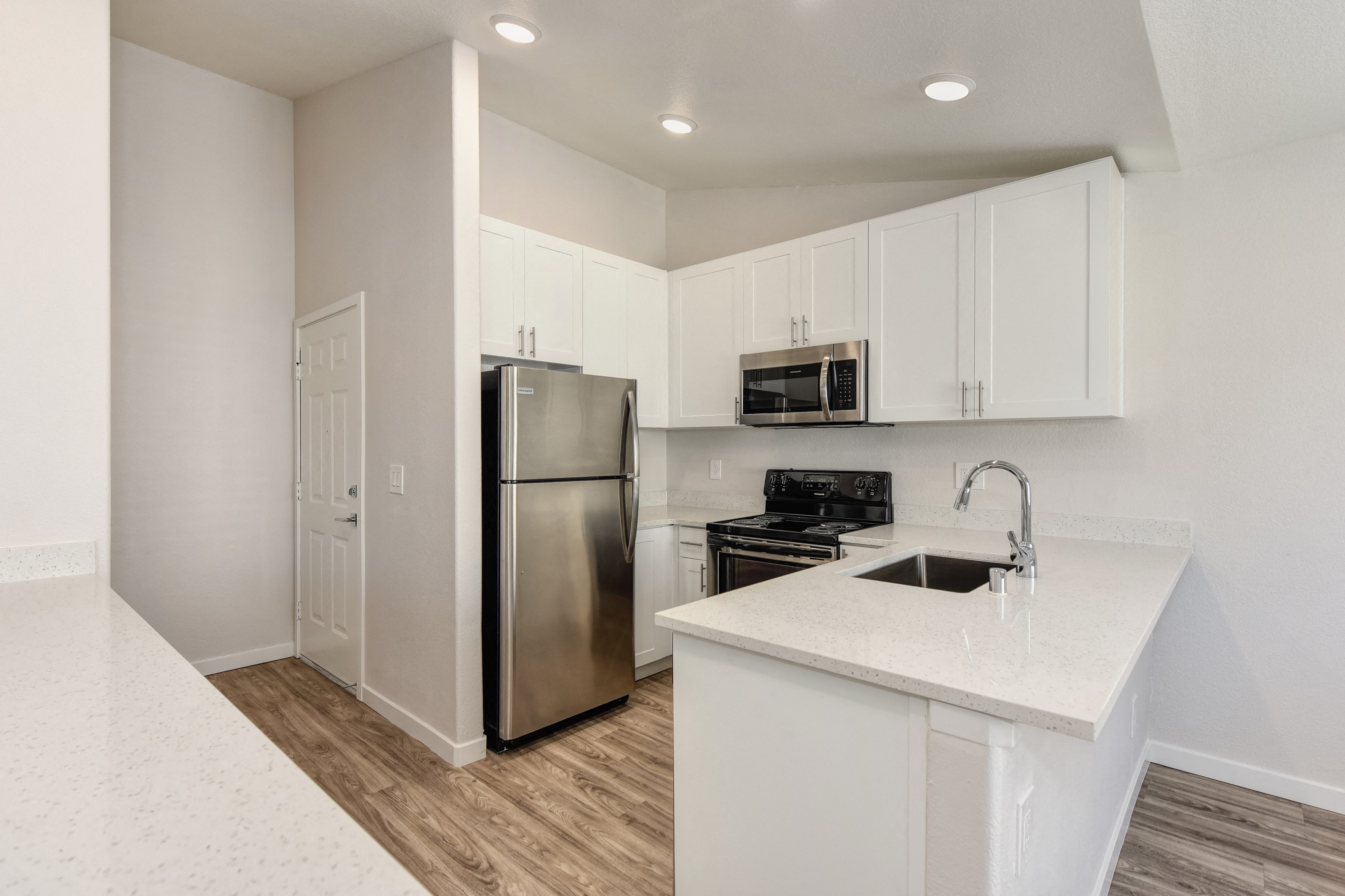 Kitchen with Dishwasher , Hardwood Inspired Floor, Oven, Microwave, White Cabinets  and Refrigerator at The Legacy Apartments, Antelope