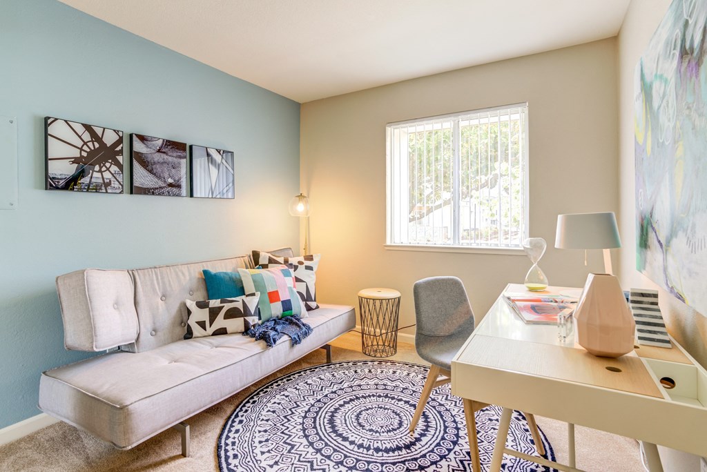 Bedroom with a futon against the baby blue accent wall and a work from home desk on the opposite wall at Addison Ranch Apartments, California