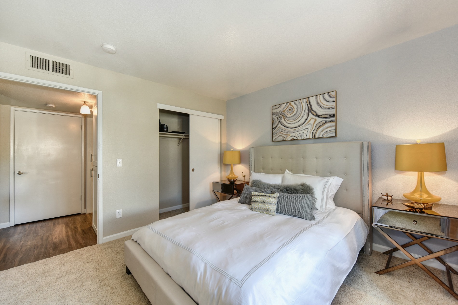 Bedroom with Large Extended Closet, Carpet, Lamps and Abstract Painting Above Bed at Cobblestone Creek Apartments, Roseville, CA, 95661