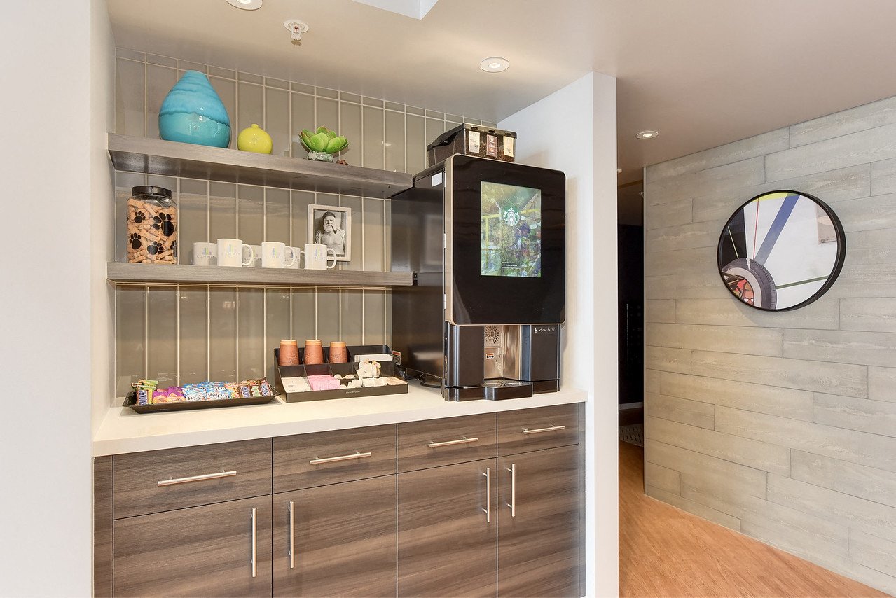 A modern kitchen with a wooden cabinet and a black microwave.
