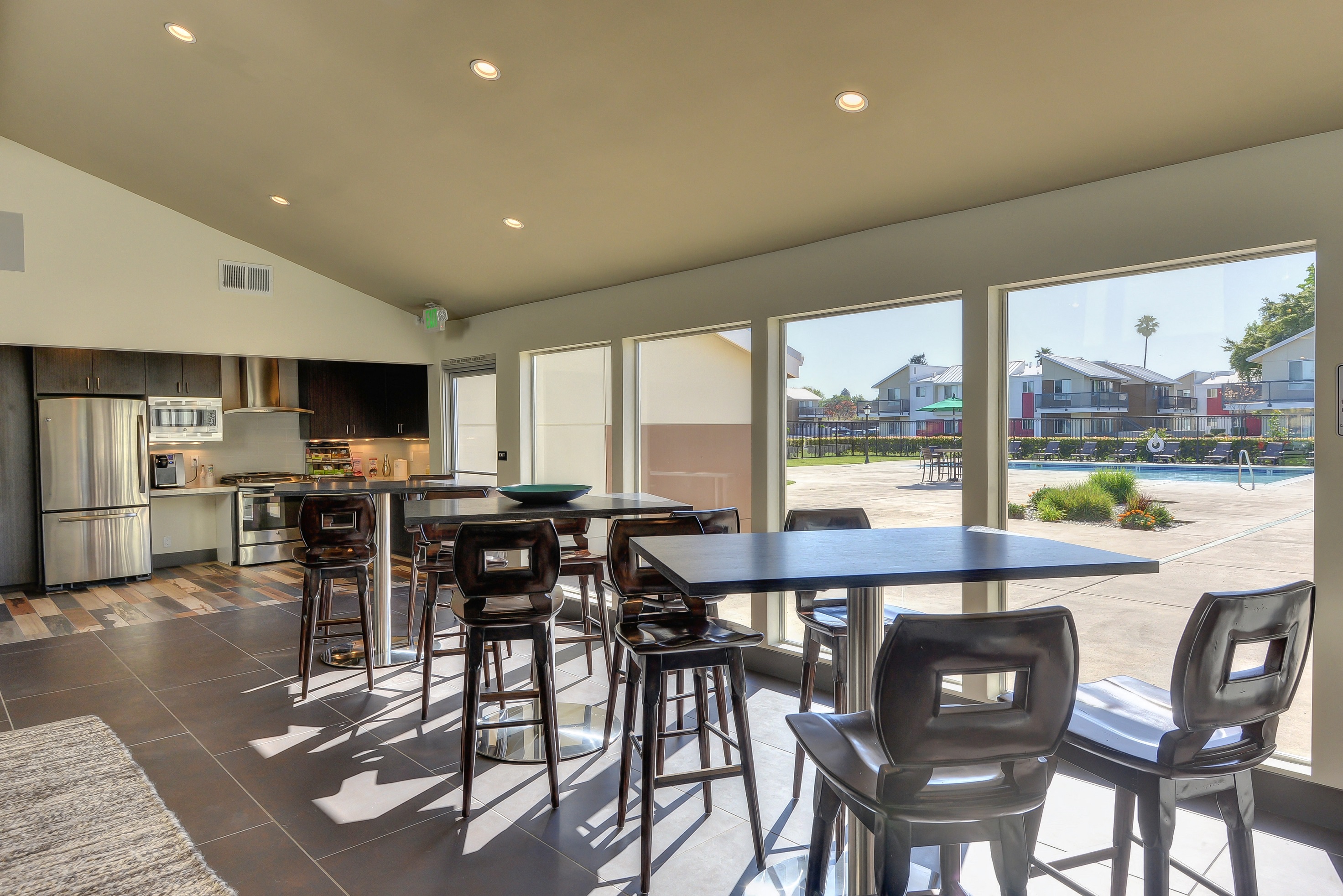 Leasing Office Dining Area, Hardwood Inspired Floors, Stool Seats, Tables, Full Windows with View of Pool, Fridge, Oven, Wood Cupboards at Addison Ranch Apartments, Petaluma, CA, 94954