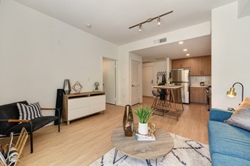 Living Room with View of Kitchen Living room with hardwood inspired flooring with a view of the kitchen and apartment entrance - Photo Gallery 6