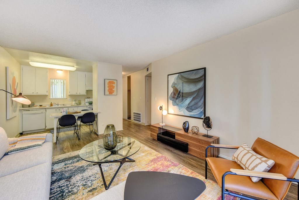 Living Room with View of Dining Area, Hardwood Inspired Floor, Colorful Rug, Brown Chair and White Sofa at Renaissance Park Apartments, Davis, CA