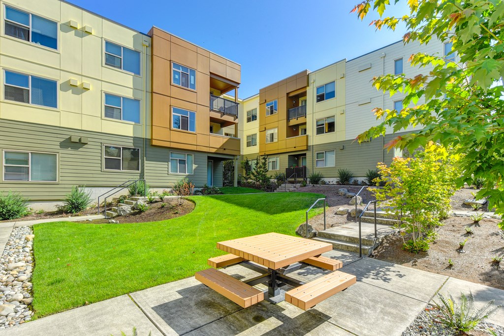 Community Open Green Spaces, with picnic bench and table with walkways around community and  Apartment buildings surrounding the courtyard area.