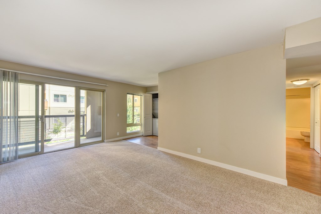 Vacant upper floor of the Kelsey /Mercer Floorplan Living Room with carpet and views of the sliding glass door which leads out to the enclosed balcony.  