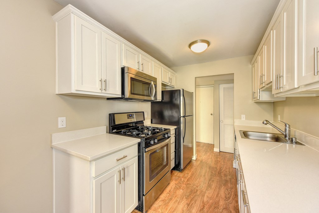 Vacant Kelsey and/or Mercer Floorplan Kitchen with all stainless steel appliances , hardwood inspired flooring and white cabinetry