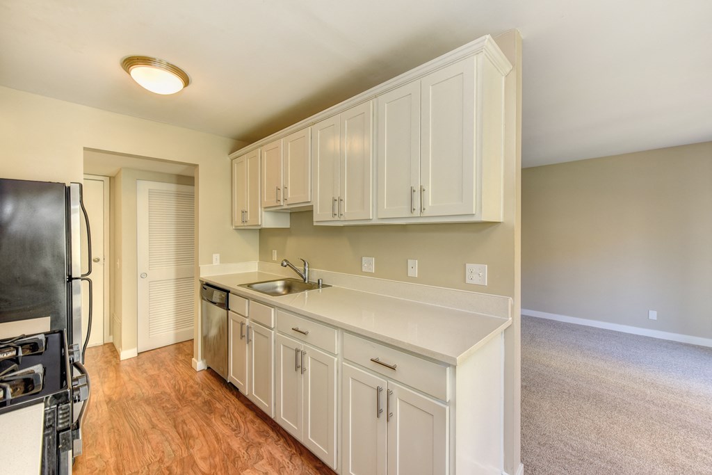 Vacant Kelsey and/or Mercer Floorplan Kitchen with all stainless steel appliances , hardwood inspired flooring and carpeting in the living room on non-ground floor homes