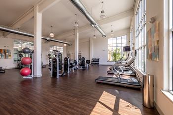 a gym with treadmills and other exercise equipment and windows