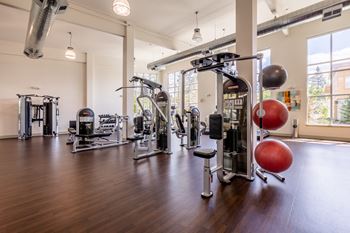 a gym with weights and other exercise equipment in a building with large windows