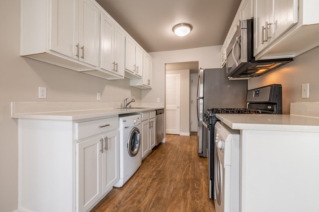 Vacant home kitchen alley with washer and dryer near the lower kitchen cabinets