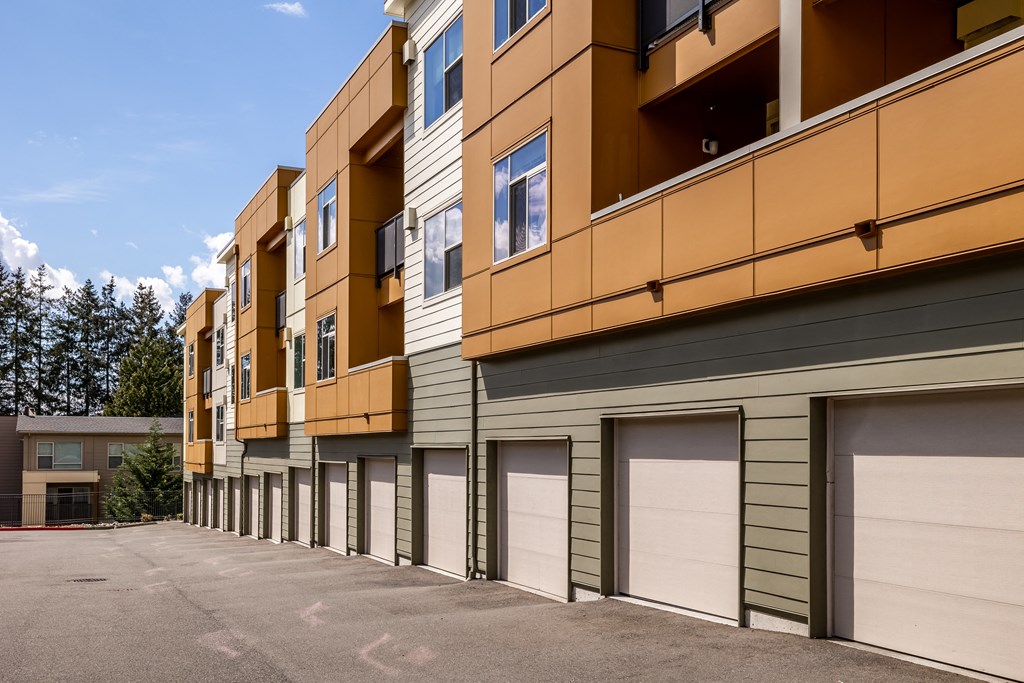 Madison Bellevue driveway outside of a long building that consists of garages at the bottom floors and apartments on upper floors of the building.
