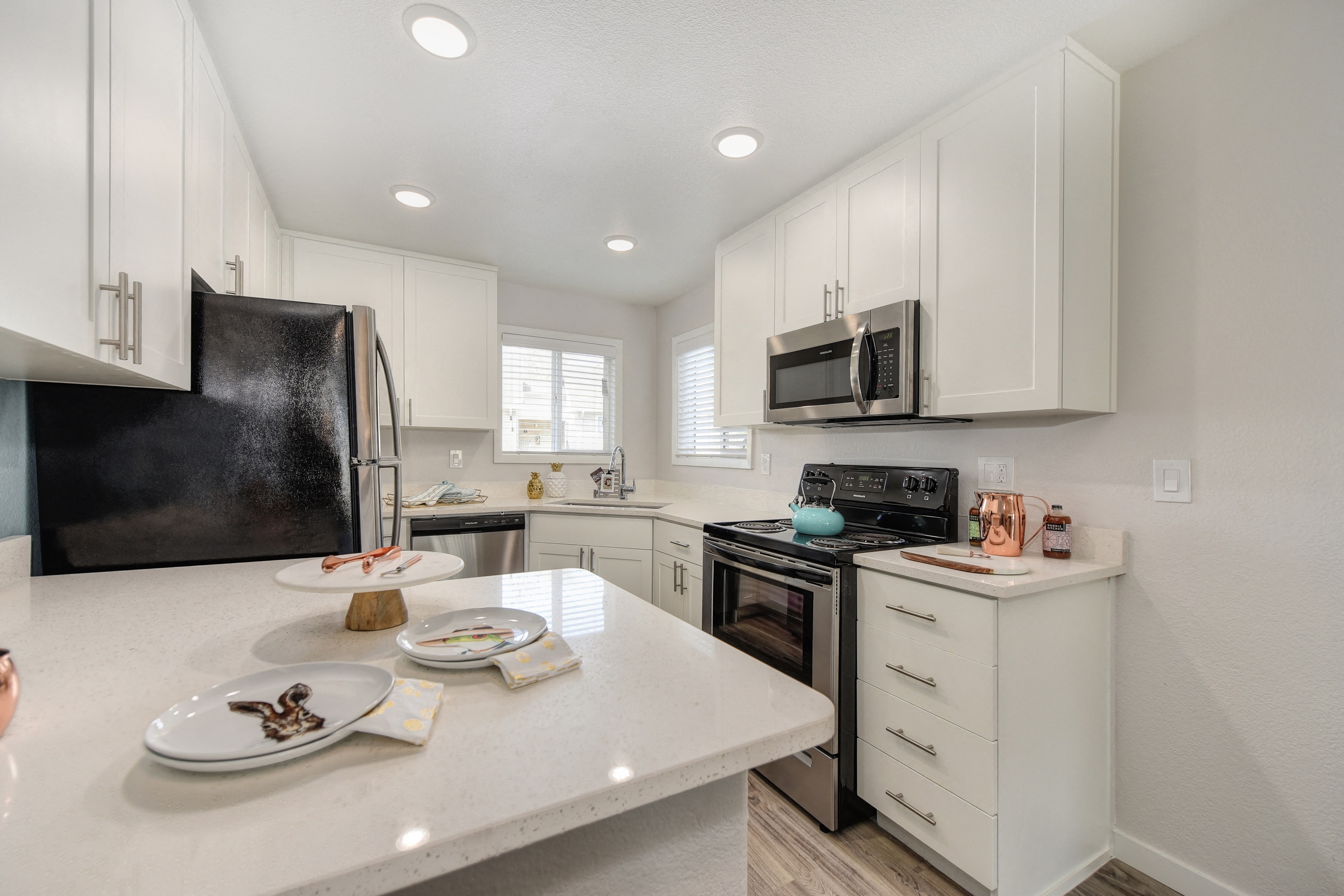 Kitchen with White Countertop, White Cabinets, Microwave and Refrigerator at The Legacy Apartments, Antelope, CA