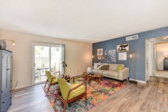 Living Room with Hardwood Inspired Floor, Lime Sofa Chairs, Gray Sofa, Colorful Rug and Sliding Door to Patio at The Renaissance Apartments, Citrus Heights, CA 95610