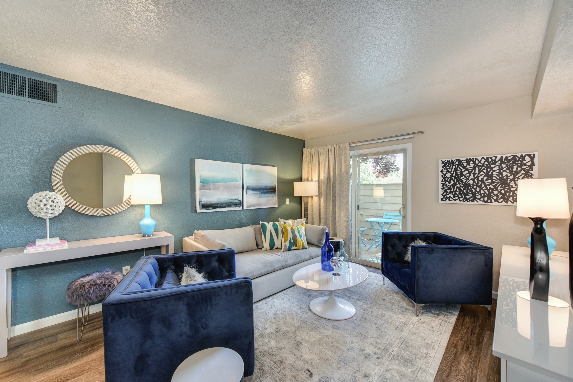 Living Room with Window,  Hardwood Inspired Floors, White Carpet, Blue Suede Chair, White Sofa, Lamps at Cobblestone Creek Apartments, Roseville, CA
