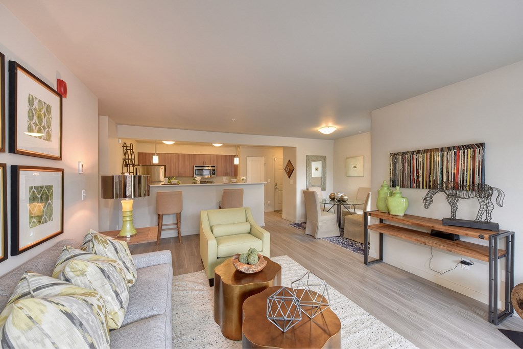 Model Living Room with View of Kitchen, White Sofa, Hardwood Inspired Floor, Lime Chairs, Ornamental Animal and Green Vase on Wood Table
