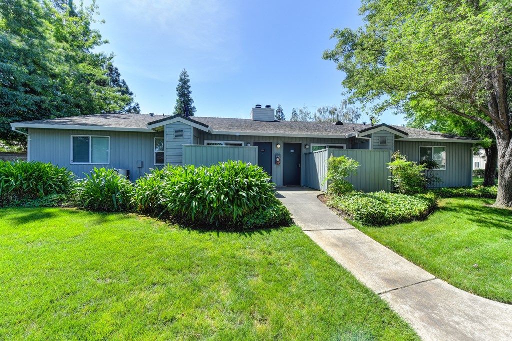 Cottages which look like single story duplexes.  Large grassy area in front of the cottages with concrete walk path leading to the doors. at Monte Bello Apartments, Sacramento