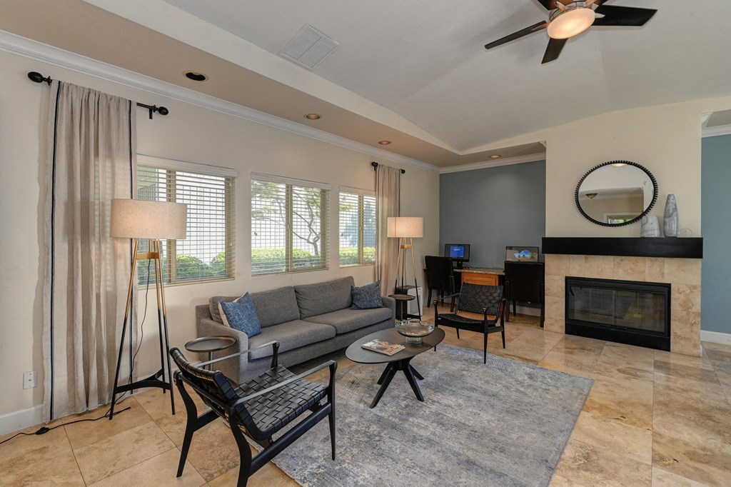 Monte Bello Leasing office with light wood floors, seating area with couch and chairs.  Fireplace with mantle and round mirror above the fireplace. at Monte Bello Apartments, Sacramento, CA, 95826